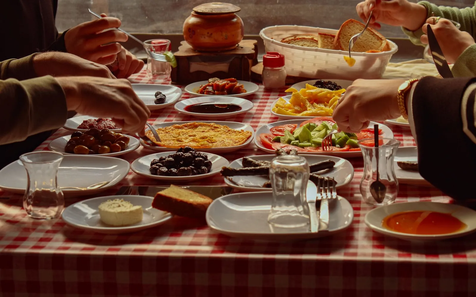 Hands reaching across a crowded family table laid with shared dishes